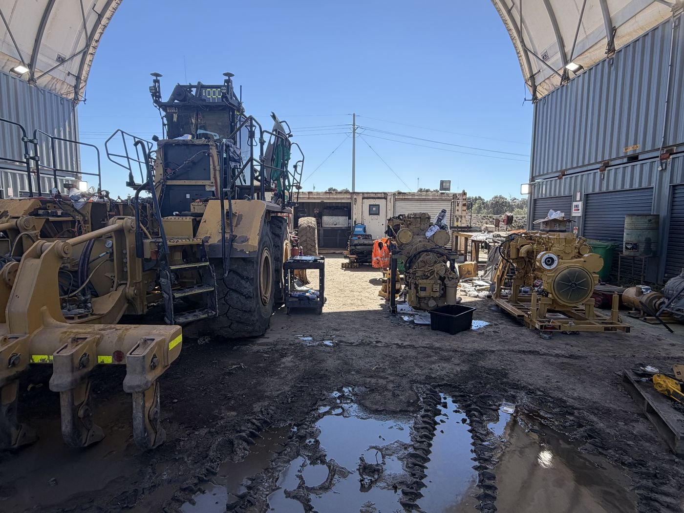 Wheel loader and rebuilt diesel engines under a field workshop shelter