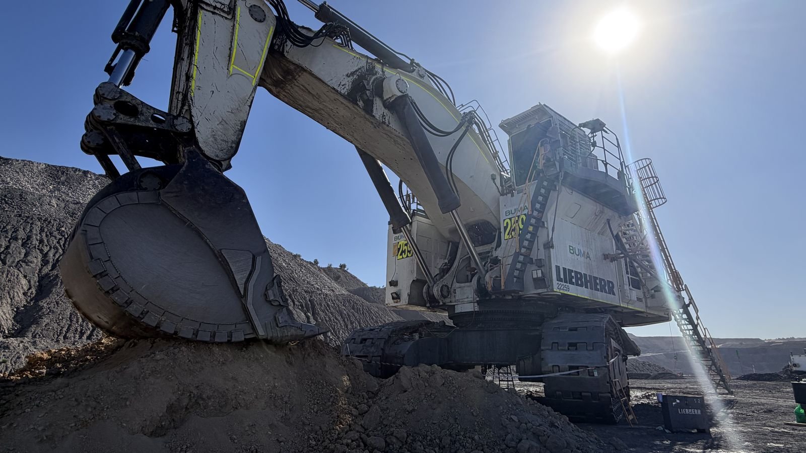Liebherr mining excavator loading at a Queensland coal mine, backlit by low sun