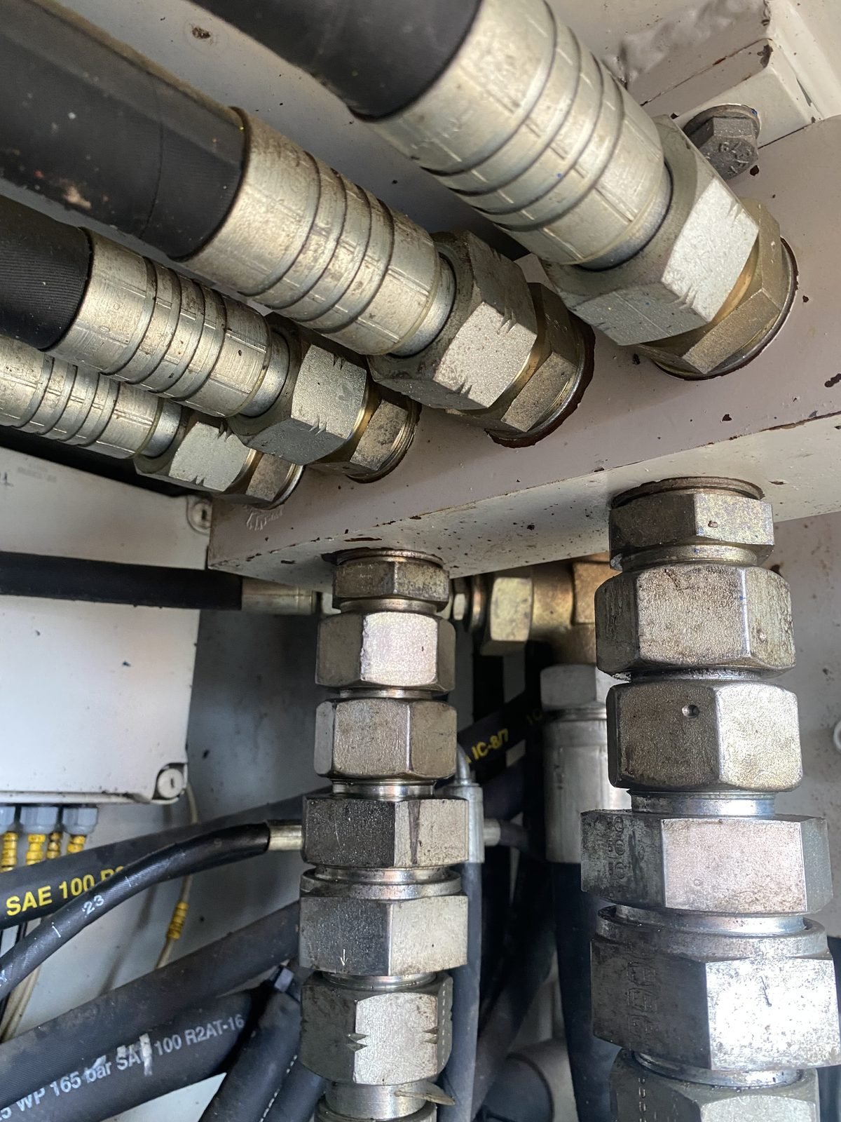 Crimped hydraulic hose ends and steel fittings inside a machine bay