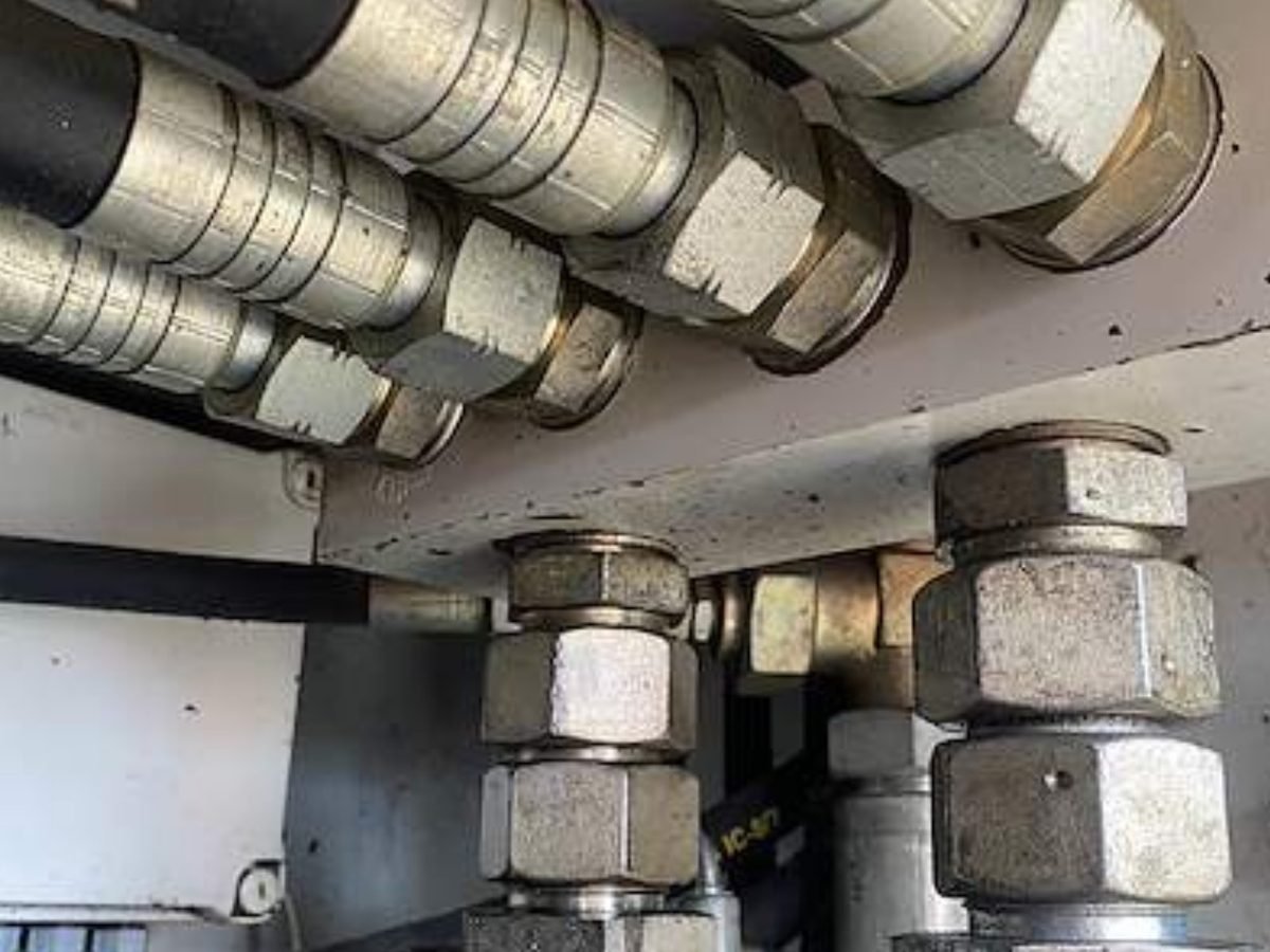 Bank of crimped hydraulic hoses and steel fittings inside a machine bay