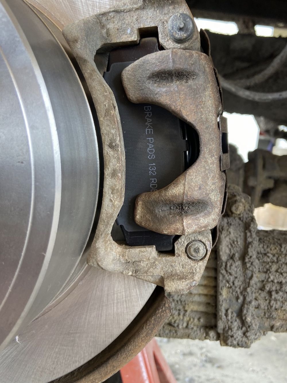 Brake rotor and caliper on a vehicle raised on a stand during a workshop service